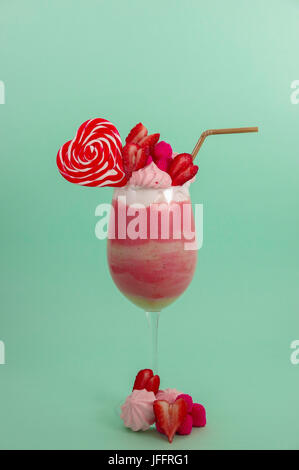 Köstliche hausgemachte extreme Milchshake Erdbeere mit Milchschaum mit einem Kunststoff Stroh und ein Bonbon rosa Blackberry mit einem Herz-Bonbon obendrauf, in ein sof Stockfoto