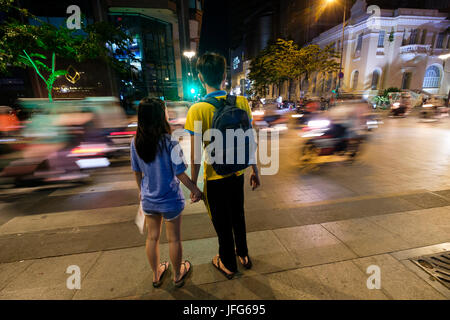 Paar wartet eine Straße in Ho Chi Minh City, Vietnam, Asien zu überqueren Stockfoto