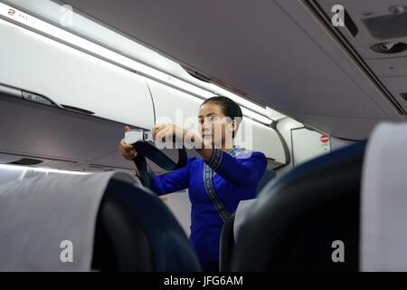 Flug Hostess in Uniform zeigen, wie das Flugzeug Sicherheitsgurt während Sicherheitsverfahren zu verwenden Stockfoto