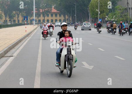 Mann, Motorroller mit einem jungen Kind auf den Straßen von Hanoi, Vietnam, Asien Stockfoto