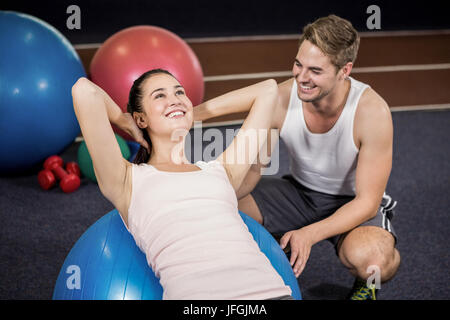 Trainer unterstützen eine Frau tut Bauch-Crunches auf Fitness-ball Stockfoto