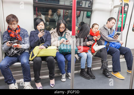 China, Hong Kong, U-Bahn Fahrgäste Verwendung elektronischer Geräte Stockfoto