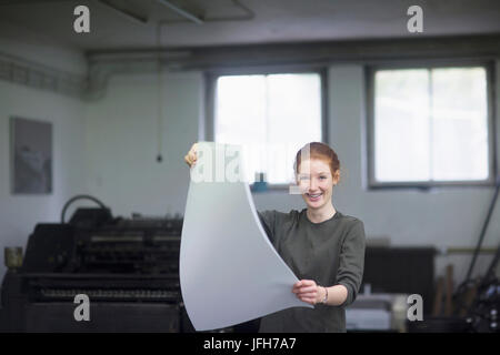 Junge Frau mit Haufen Papier an Druckmaschine Stockfoto