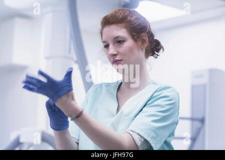 Junge weibliche Krankenschwester anziehen Handschuhe Stockfoto