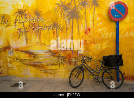 Fahrrad an der bemalten Wand lehnt Stockfoto