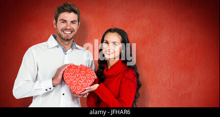 Zusammengesetztes Bild des Paares hält Herz geformt Geschenk-box Stockfoto