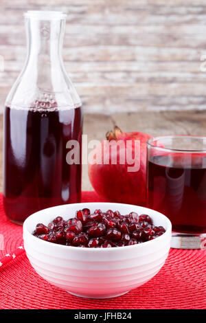 Granatapfel Samen mit Saft in ein Glas und eine Flasche Stockfoto