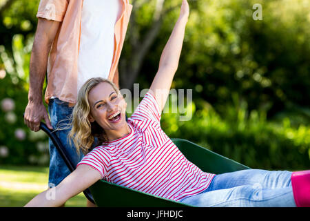 Mann, die Frau sitzt in Schubkarre am Hof schieben Stockfoto