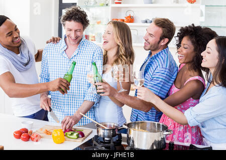 Gruppe von Freunden Toasten von Bier und Wein Gläser in Küche Stockfoto