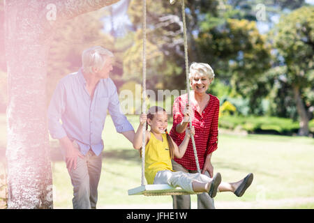 Die Großeltern ihre Enkelin Drücken auf Swing Stockfoto