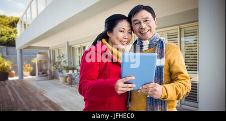 Zusammengesetztes Bild des asiatischen paar auf Balkon mit tablet Stockfoto