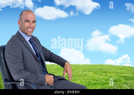 Das zusammengesetzte Bild im Hochformat in der zuversichtlichen Unternehmer sitzen auf Stuhl Stockfoto