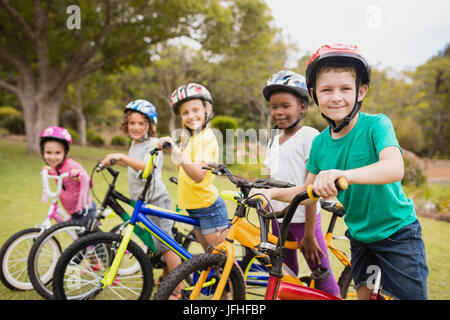 Kinder Tragen von Helm und auf ihrem Fahrrad posing Stockfoto