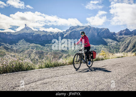 Frau Reiten-Elektro-Fahrrad auf Bergstraße Stockfoto