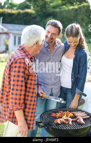 Paar mit älteren Menschen die Zubereitung von Speisen am Grill Stockfoto