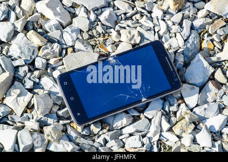 Frustriert Telefon auf den Felsen. Glas zerbrochen auf Felsen auf einem Smartphone. Smartphone fiel und stürzte ab. Stockfoto