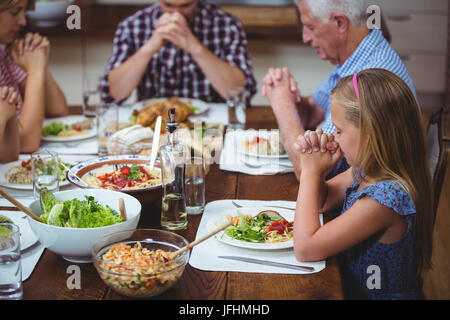 Multi-generation Familie beten mit Opa am Esstisch sitzen Stockfoto