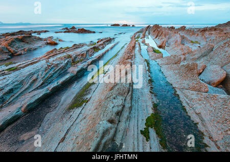 Twilight Ozean Küste mit geripptem stratiform Rock. Stockfoto