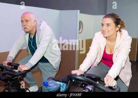 ältere Menschen und junge Dame an der statischen Zyklus Maschinen Stockfoto