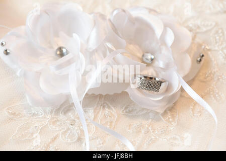 Ring aus Platin mit Diamanten vor weißen Textilblumen auf einem Hintergrund von lacy gemacht Stockfoto