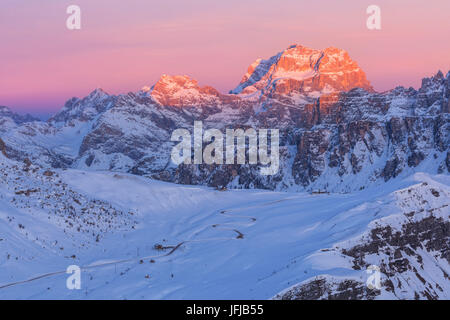 Die Straße, die zum Passo Giau bei einem Winter Sonnenuntergang im Hintergrund Sorapiss geht beleuchtet durch die letzten Strahlen der Sonne bei Dämmerung, Dolomiten, Veneto, Italien Stockfoto