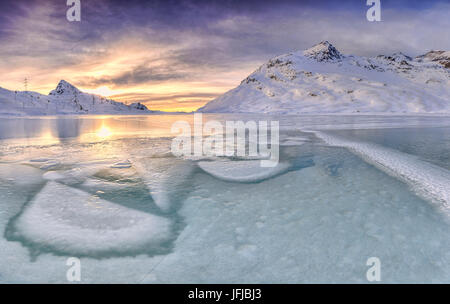 Sunrise leuchtet die Tiefkühlkost Oberfläche Ordnung White Lake am Berninapass, Kanton Graubündens, Engadin, Schweiz, Europa Stockfoto