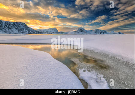 Die goldene Sonnenaufgang spiegelt sich in einem Pool an das klare Meer, wo der Schnee ist fast geschmolzen, Haukland Lofoten Inseln Norwegen Europa Stockfoto