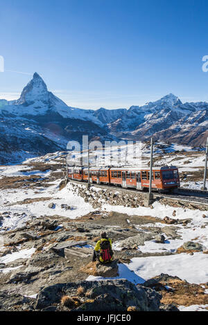 Wanderer bewundert Matterhorn, während weiße Zug der Gornergrat im Hintergrund, Zermatt, Kanton Wallis, Schweiz-Europa fährt Stockfoto