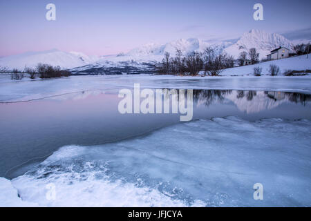 Schneebedeckte Gipfel spiegeln sich in den gefrorenen See Jaegervatnet bei Sonnenuntergang Stortind Lyngen Alpen Tromsø Lappland Norwegen Europa Stockfoto