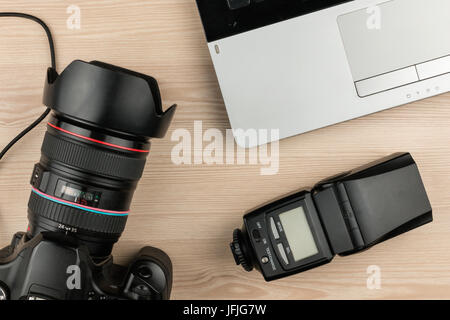 Arbeiten Tisch Fotograf Draufsicht, Holzoberfläche mit Laptop, Kamera und Blitz. Ansicht von oben Stockfoto