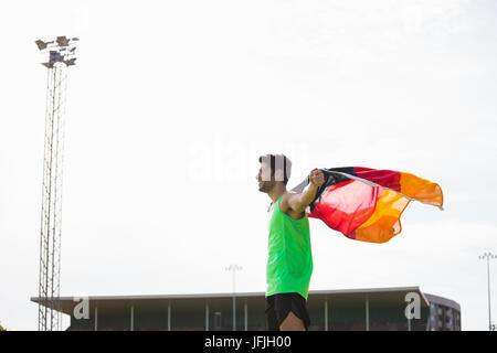 Athlet posiert mit deutscher Flagge nach Sieg im Stadion Stockfoto