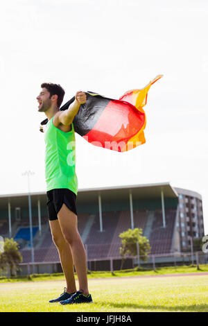 Athlet posiert mit deutscher Flagge nach Sieg im Stadion Stockfoto