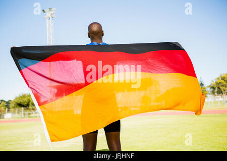 Athlet posiert mit deutscher Flagge nach Sieg Stockfoto