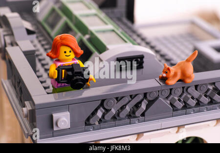 Tambow, Russische Föderation - 21. Januar 2017 Lego Mädchen mit Kamera nehmen Foto auf Dach. Rote Katze sitzt auf dem Geländer. Studio gedreht. Stockfoto