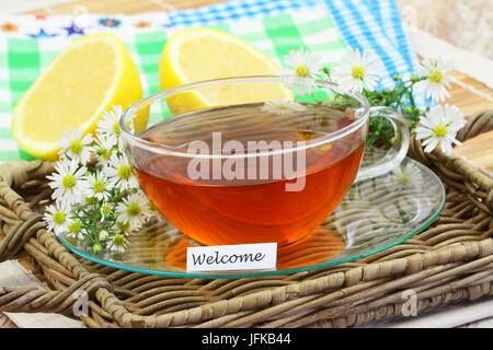 WelcomeCard mit Tasse Tee, Kamillenblüten und Zitrone Stockfoto