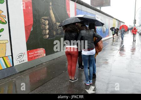 Berlin, Deutschland. 1. Juli 2017. Touristen tragen Regenschirme bei Regen an der East Sidie Gallery in Berlin, Deutschland, 1. Juli 2017. Foto: Maurizio Gambarini/Dpa/Alamy Live News Stockfoto