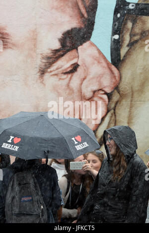 Berlin, Deutschland. 1. Juli 2017. Touristen tragen Regenschirme bei Regen an der East Sidie Gallery in Berlin, Deutschland, 1. Juli 2017. Foto: Maurizio Gambarini/Dpa/Alamy Live News Stockfoto