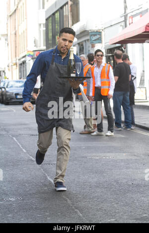 Soho, London. 2. Juli 2017. Londoner Restaurantpersonal sprint durch die Straßen von Soho mit einem Tablett in der Hand, beladen mit einer Serviette, eine halbe Flasche Champagner und einem Sektglas, Beschaffung von Mitteln für neue Wohltätigkeitsorganisation der Kellner Unterstützungskasse für angeschlagene Kellner Credit: Amer Ghazzal/Alamy Live-Nachrichten Stockfoto