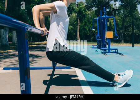 Nahaufnahme einer jungen sportlichen Frau Übungen für den Trizeps auf dem Spielplatz im Sommer. Konzept eines gesunden Lebensstils. Stockfoto