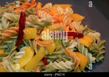 Fusilli Nudeln mit Knoblauch, getrocknete rote Chili, gelbe Paprika und Olivenöl in einer Pfanne gekocht wird Stockfoto