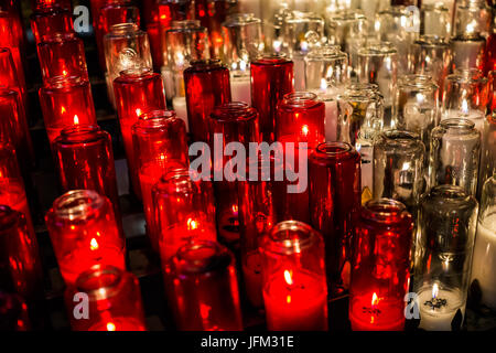 Makro Nahaufnahme von roten und weißen Kerzen mit gelben Flamme in der Kirche Stockfoto