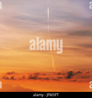 Flugzeug fliegen über orange Sonnenuntergang Himmel, der aussieht wie Rakete gestartet Stockfoto