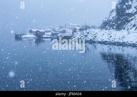 Schneefall in einer kleinen Bucht von Nusfjord Fischerdorf, Lofoten Inseln, Norwegen Stockfoto