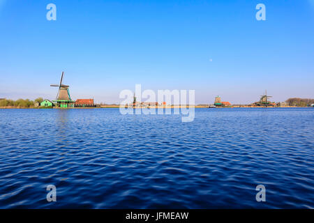 Typische Windmühlen spiegelt sich im blauen Wasser des Flusses Zaan im Frühjahr Zaanse Schans Nord Holland-die Niederlande Europa Stockfoto