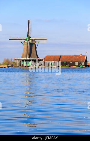 Typische Windmühle spiegelt sich im blauen Wasser des Flusses Zaan im Frühjahr Zaanse Schans Nord Holland-die Niederlande Europa Stockfoto