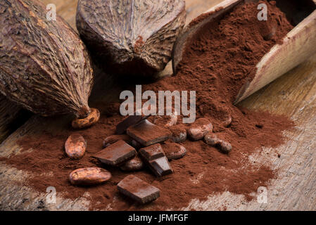 Kakaofrüchte mit Kakaobohnen, Kakaopulver und Schokolade Block auf Holztisch Stockfoto