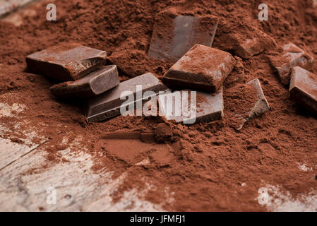 Haufen von Kakaopulver mit Schokolade Block auf Holztisch Stockfoto