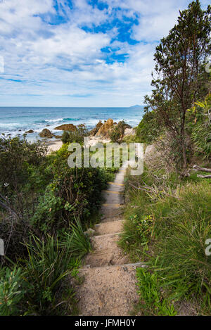 Ein schmaler sandiger Pfad führt zum blauen Himmel und den goldenen Sandstrand von einem Strand bei Hallidays Punkt an der Nordküste von New South Wales Stockfoto