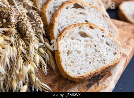 Vollkornbrot mit Ähren und Samen, Brotscheiben auf Holzbrett Stockfoto