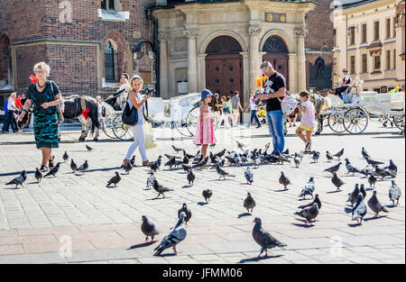 KRAKAU, POLEN - 1. SEPTEMBER 2016. Menschen und Tauben, Touristen-Attraktion in Rynek Glowny, Marktplatz in der Altstadt von Krakau, Polen. Stockfoto